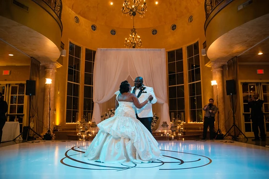 A couple shares a dance on a lit-up floor at an event planning-driven wedding reception hall.