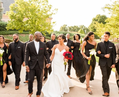 A radiant wedding party walking joyfully with the bride and groom leading the way.